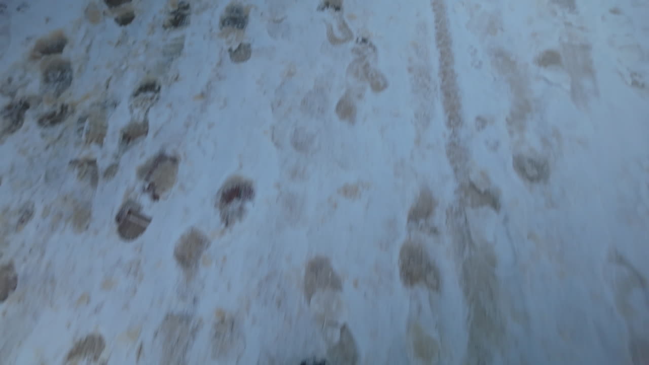 Primo piano di stivali che camminano su un marciapiede innevato con impronte visibili e texture invernali nella zona della città vecchia
