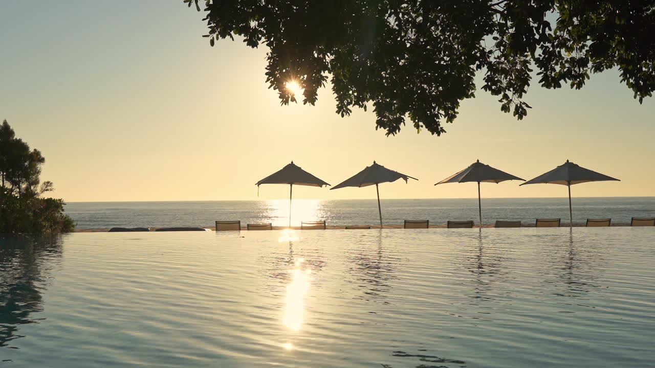 Picturesque Poolside Scenery, Static View on Pool, Parasols and See Skyline Under Evening Sunlight