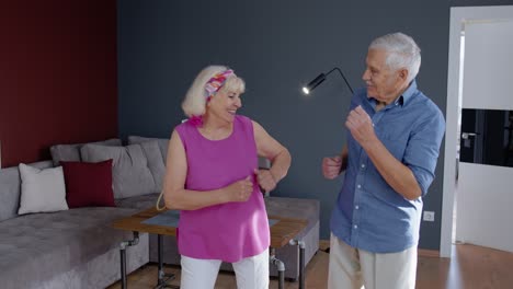 senior couple dancing laughing at home. grandparents relaxing having fun celebrating anniversary