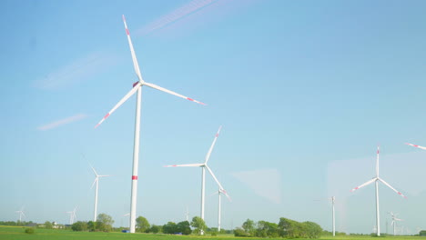 Panoramic-View-from-train-window-of-Wind-Turbines-on-Green-Fields-in-Northern-Germany