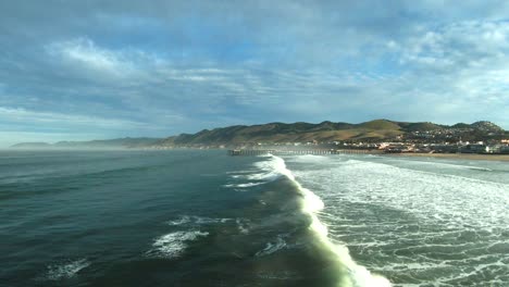 volando justo por encima del punto donde rompen las olas hacia el emblemático muelle de pismo beach