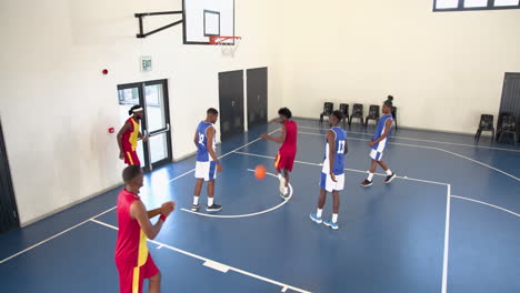 multiracial male basketball players playing basketball, passing and throwing basketball in gym