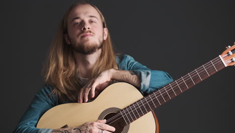 caucasian young man posing with guitar on camera.