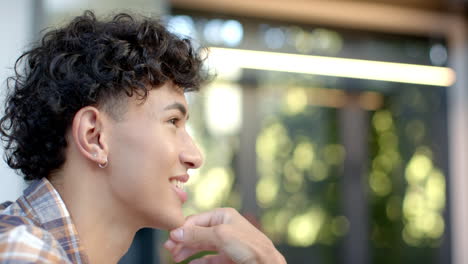 smiling young man with curly hair looking away, enjoying peaceful moment at home, copy space
