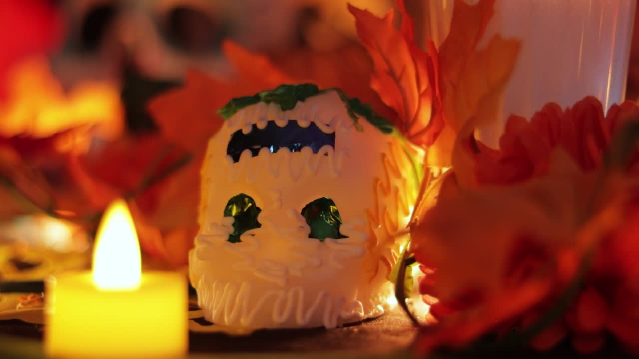 Sugar skull offering and burning candle on Día de los Muertos altar