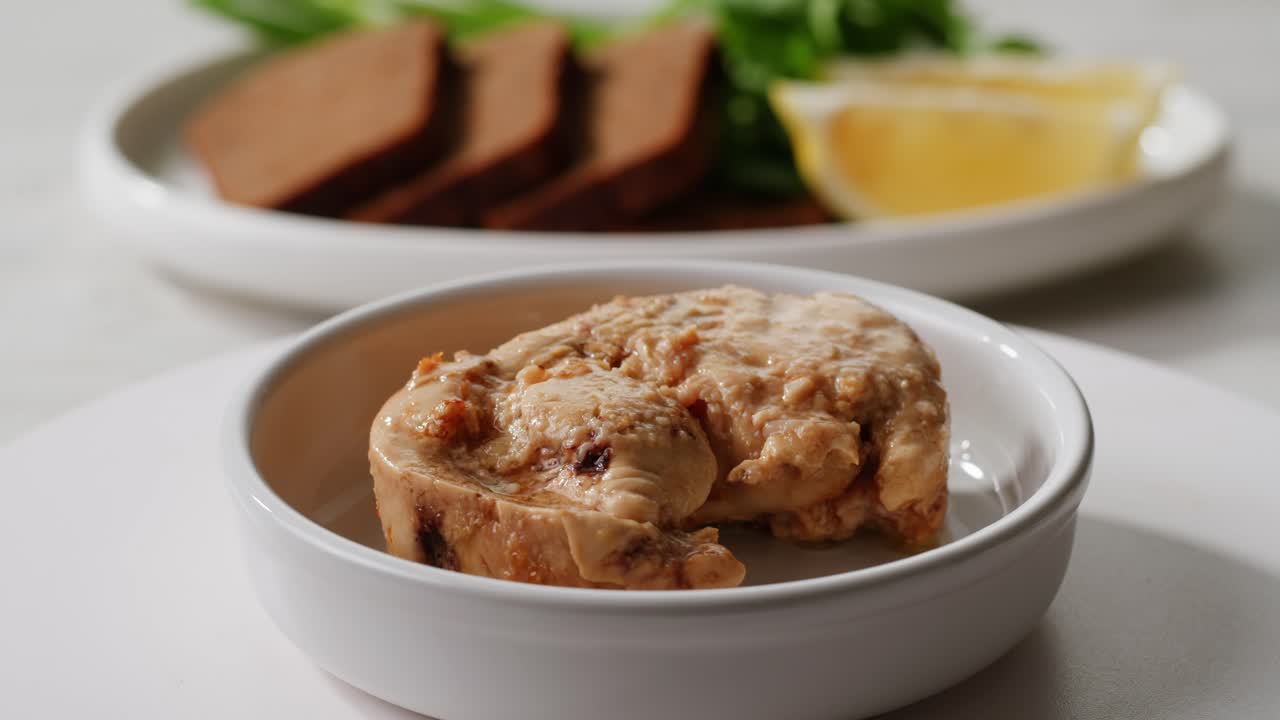 Smoked cod liver in oil in open tin can with fresh greens on wooden table. Seafoods delicacy. High quality 4k footage