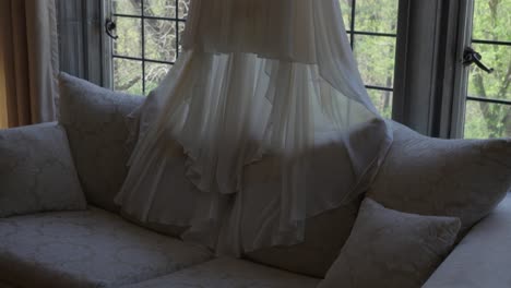 vestido de novia blanco colgado frente a las ventanas de plomo de la casa señorial, panorámica hacia abajo disparado