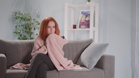 woman covered with blanket watches dramatic movie on tv