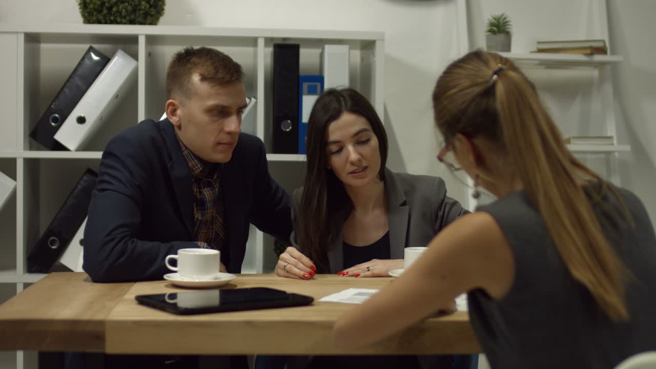 счастливая пара подписывает контракт вместе в офисе