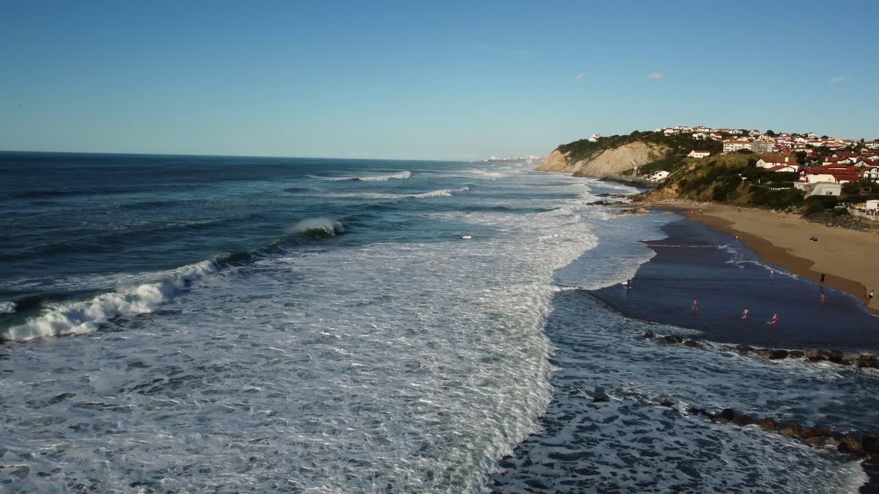 Aerial view of a beach with waves and a cliff
