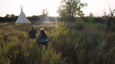 drone shot of two mature women camping in teepee in field meeting with friends