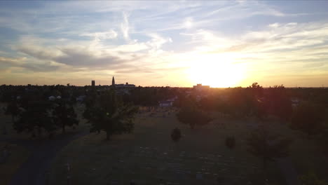 ascending aerial shot of the sun setting over the graveyard