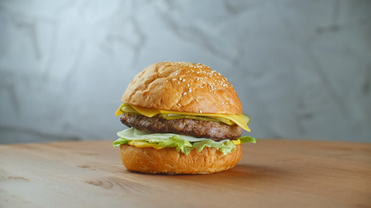 una hamburguesa grande y sabrosa con carne, cebollas, verduras, queso derretido y lechuga.