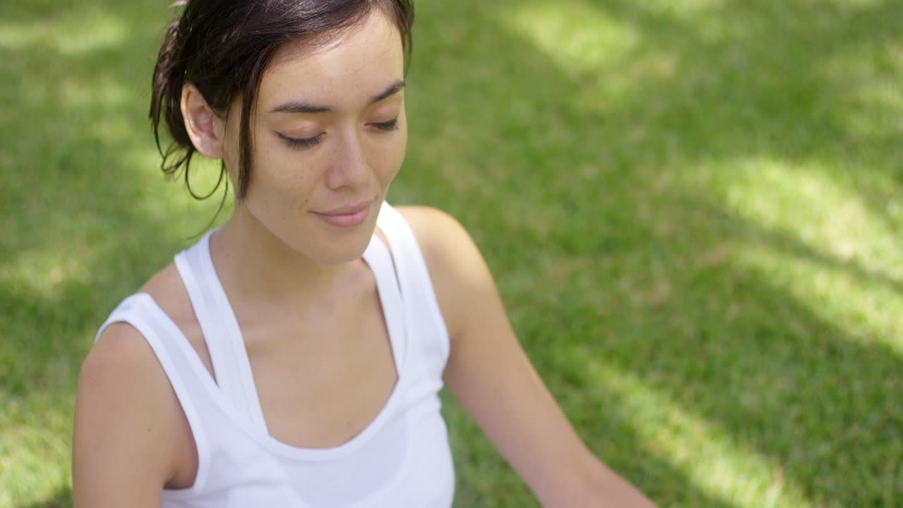 녹색 잔디밭에서 명상하는 고요한 젊은 여성