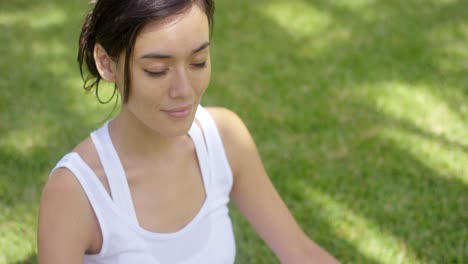 Serene-young-woman-meditating-on-a-green-lawn