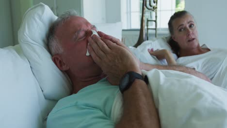 sick caucasian senior man coughing while lying in the bed at home