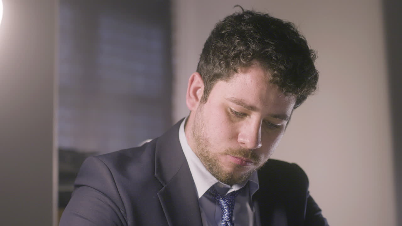 Primo piano di giovane uomo dai capelli scuri che scrive qualcosa.