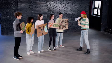 young female environmental leader with megaphone motivating her friends to protest against climate change inaction