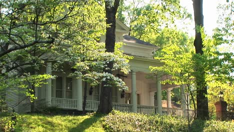 a mediumshot of a lovely old white house hidden in the trees