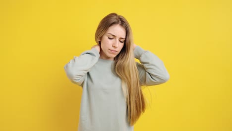 young woman massaging neck on yellow background