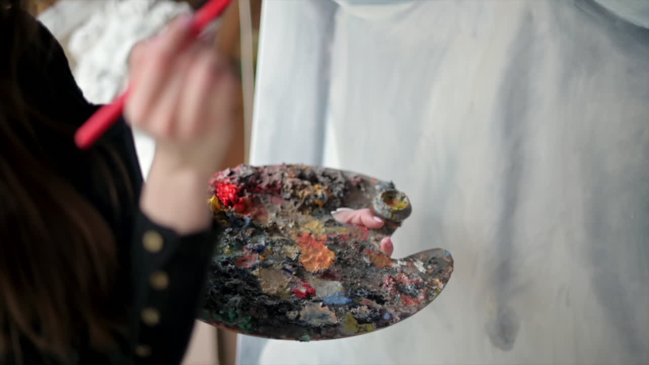 Woman painting a female body on a canvas at an art gallery workshop