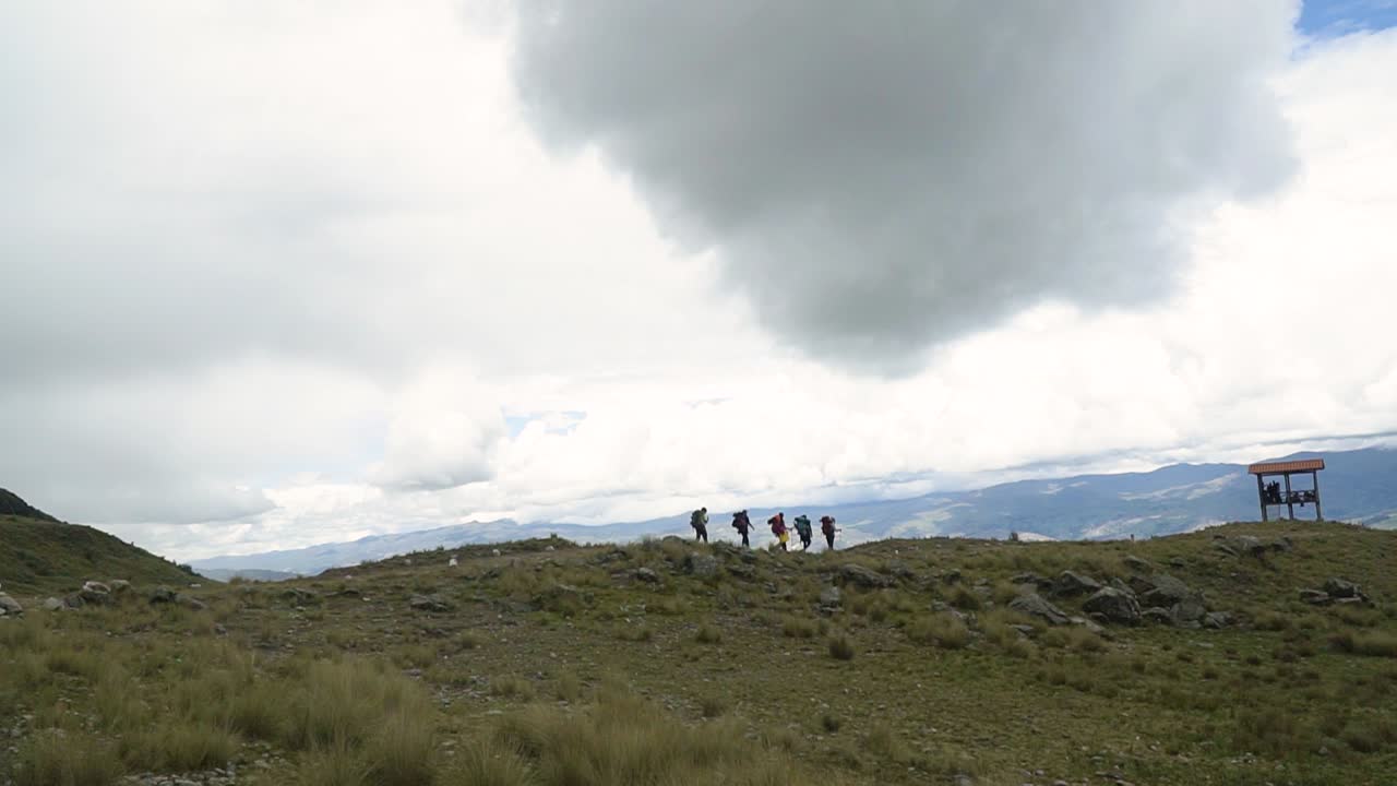 Backpackers On Mountain Trails Against Cloudy Sky In Huaraz, Peru. Wide Shot