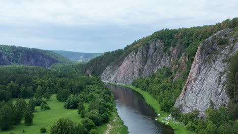 a view of the river flowing near the big cliffs. the concept of outdoor activities, water tourism. several groups of rowers on inflatable boats swim along the river.