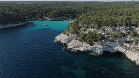 drone flying over hidden cove where boats can be seen anchored and limestone cliffs lining the inlet