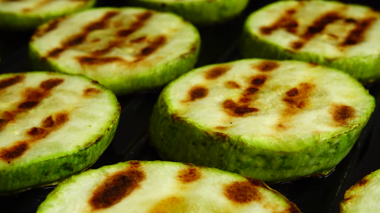 las rebanadas de calabacín frito giran en una sartén de parrilla.