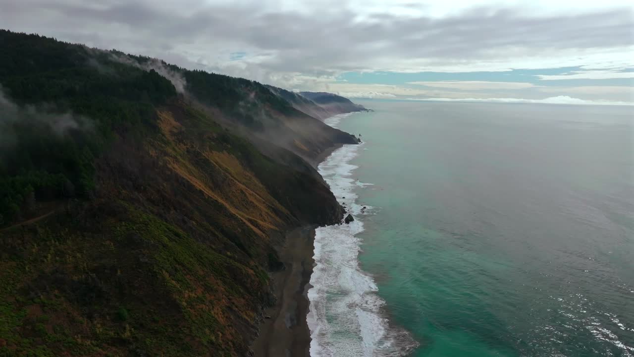 Rugged remote untouched black sand beach USAL Beach Sinkyone Wilderness Northern California aerial drone waves crashing mist fog rain coastline bluffs Lost Coast Trail forward down motion