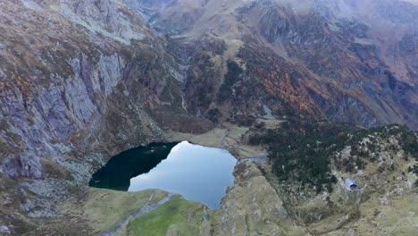 Lac-d'Espingo-lake-panoramic-high-view-in-Haute-Garonne,-Pyrénées-mountains,-France,-Aerial-orbit-above-shot