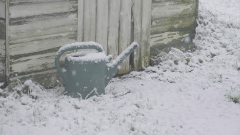 Toma-En-Tiempo-Real-De-Una-Fuerte-Caída-De-Nieve-En-Un-Jardín-Inglés-Con-Un-Cobertizo-Y-Una-Regadera