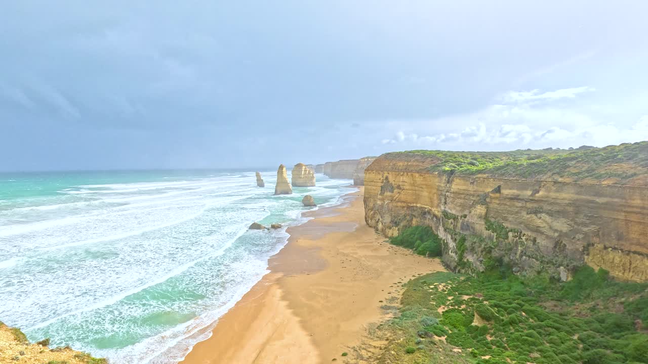 A sweeping view of the Twelve Apostles along the Great Ocean Road, showcasing dramatic cliffs and ocean waves under bright daylight