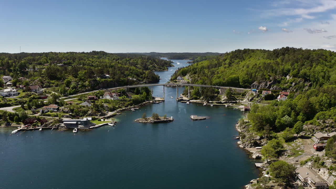 Aerial Drone shot of of Justøy Bridge in Lillesand, Norway. Drone flys towards bridge while a boat sails through the bridge on the water