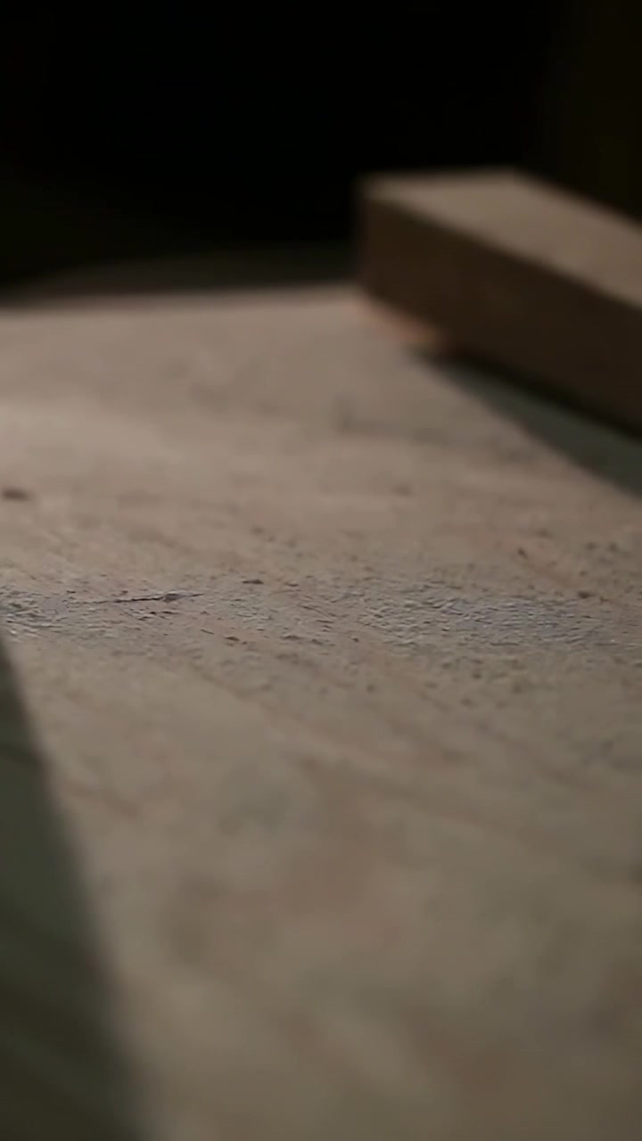 Video verticale: Piede nudo che solleva il tallone e rotola su una panca, mano che spinge un blocco mostrando una moneta, gamba del pantalone.