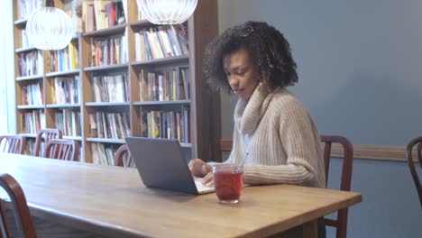 mujer estudiante casual sentada en una cafetería y usando una computadora portátil