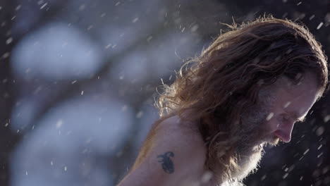 bare chested scraggy man in pain stands in snowfall then enters steaming sauna