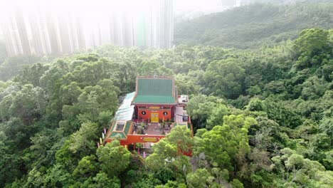 Templo-Clásico-En-Hong-Kong,-Rodeado-De-Un-Exuberante-Terreno-Montañoso-Verde,-Vista-Aérea