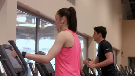 Man-and-woman-using-the-cross-trainers-in-gym