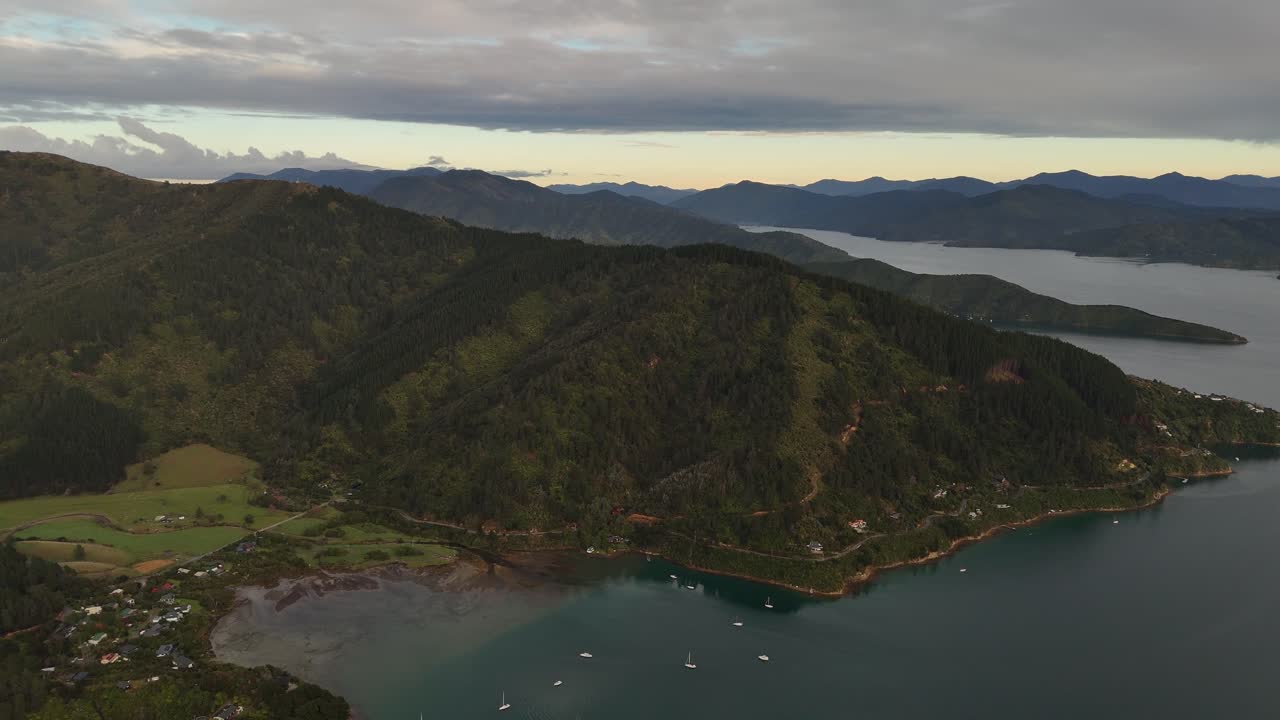 Marlborough Sounds and Cook Strait at sunrise, lush green hills, and sailboats on calm water, Picton, New Zealand. Aerial drone panoramic view