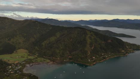 marlborough sounds and cook strait at sunrise, lush green hills, and sailboats on calm water, picton, new zealand. aerial drone panoramic view