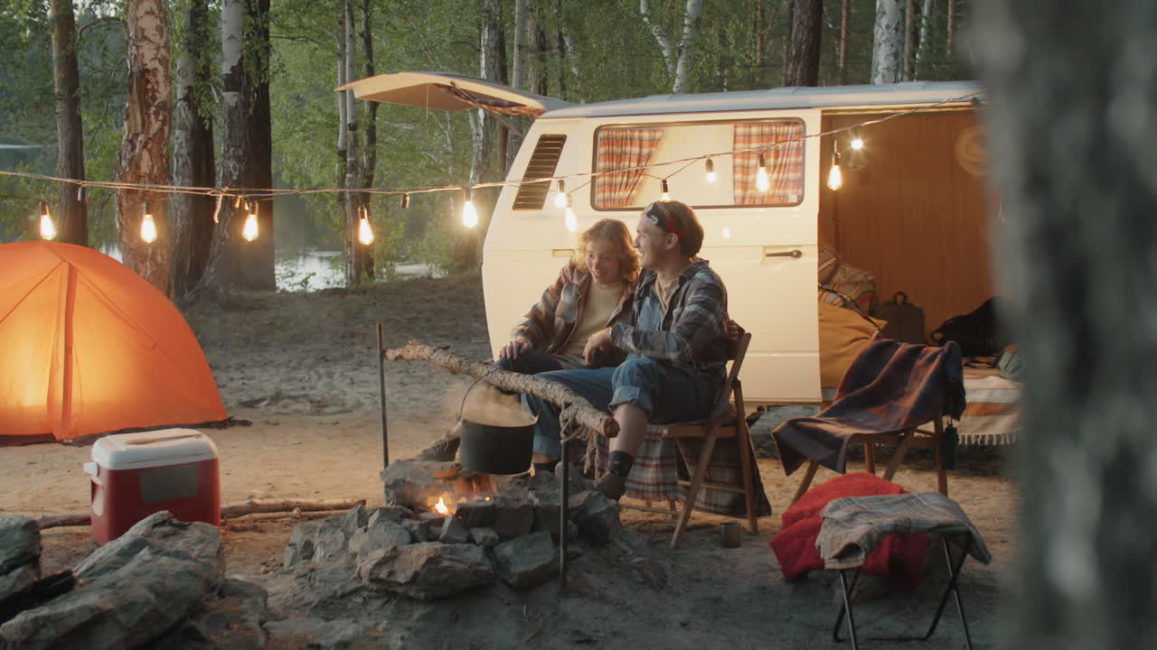 저녁 에 캠프 불 근처 에서 휴식 하는 젊은 부부