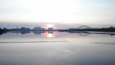 low flying shot over water of a city skyline in beautiful twilight