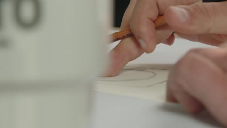el diseñador dibuja un boceto de un frasco de perfume con un lápiz: el proceso de diseño del embalaje