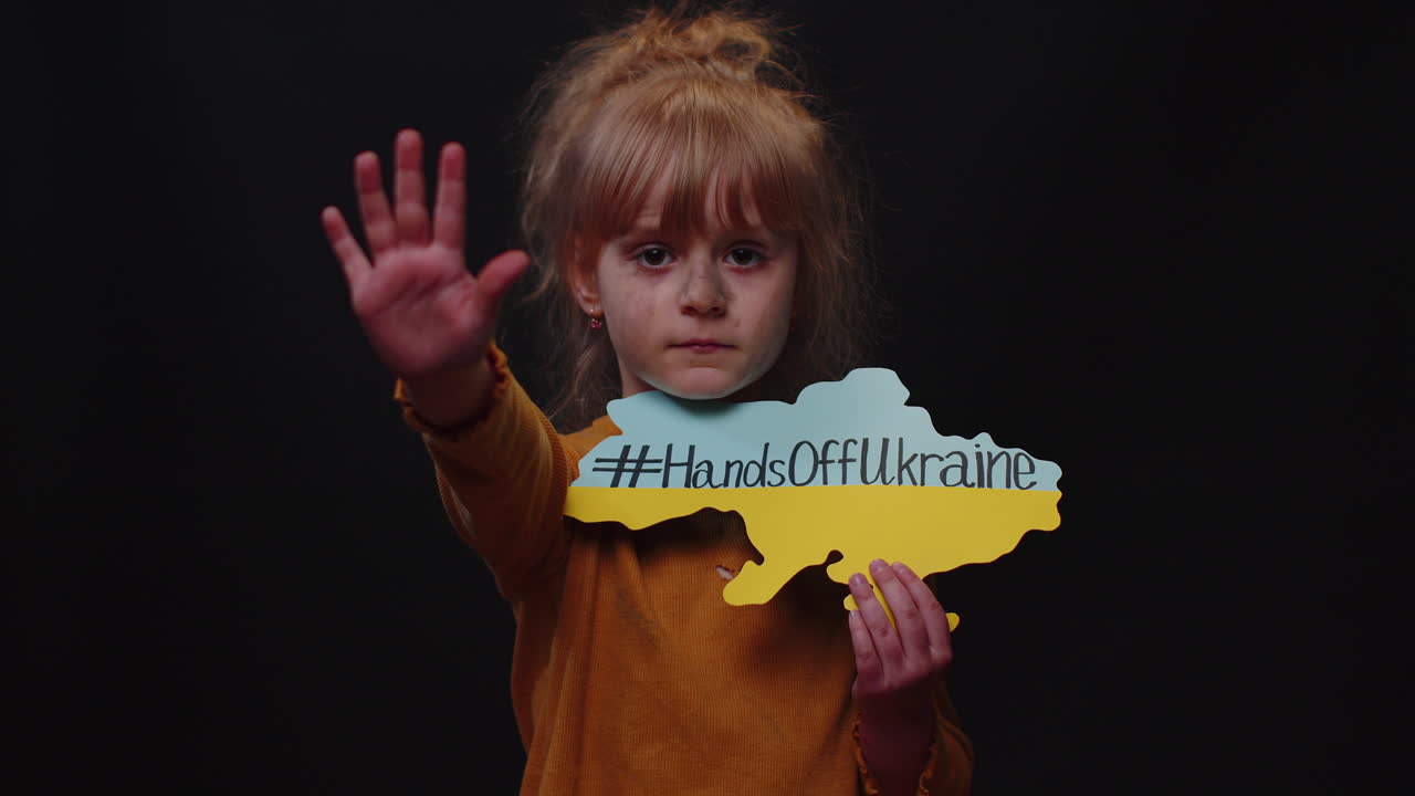Hjemløs ukrainsk jente med budskapstekst på et kart: «Hands Off Ukraine», krise, krig.