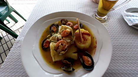 a reveal shot of a sea cuisine and a glass of drink placed on a white table