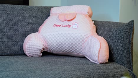 close-up of hand pressing soft pink cushion labeled “good lucky”—ideal for comfort, lifestyle, or decor content