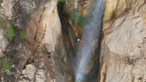 climber descending by waterfall. slow motion aerial shot