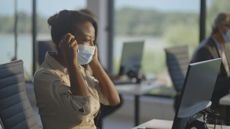 woman working in a call center, wearing a headset and a mask.