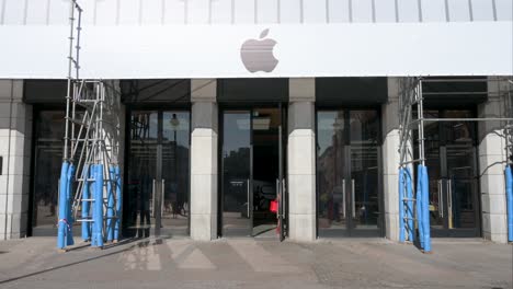 apple store entrance with scaffolding and people walking outside